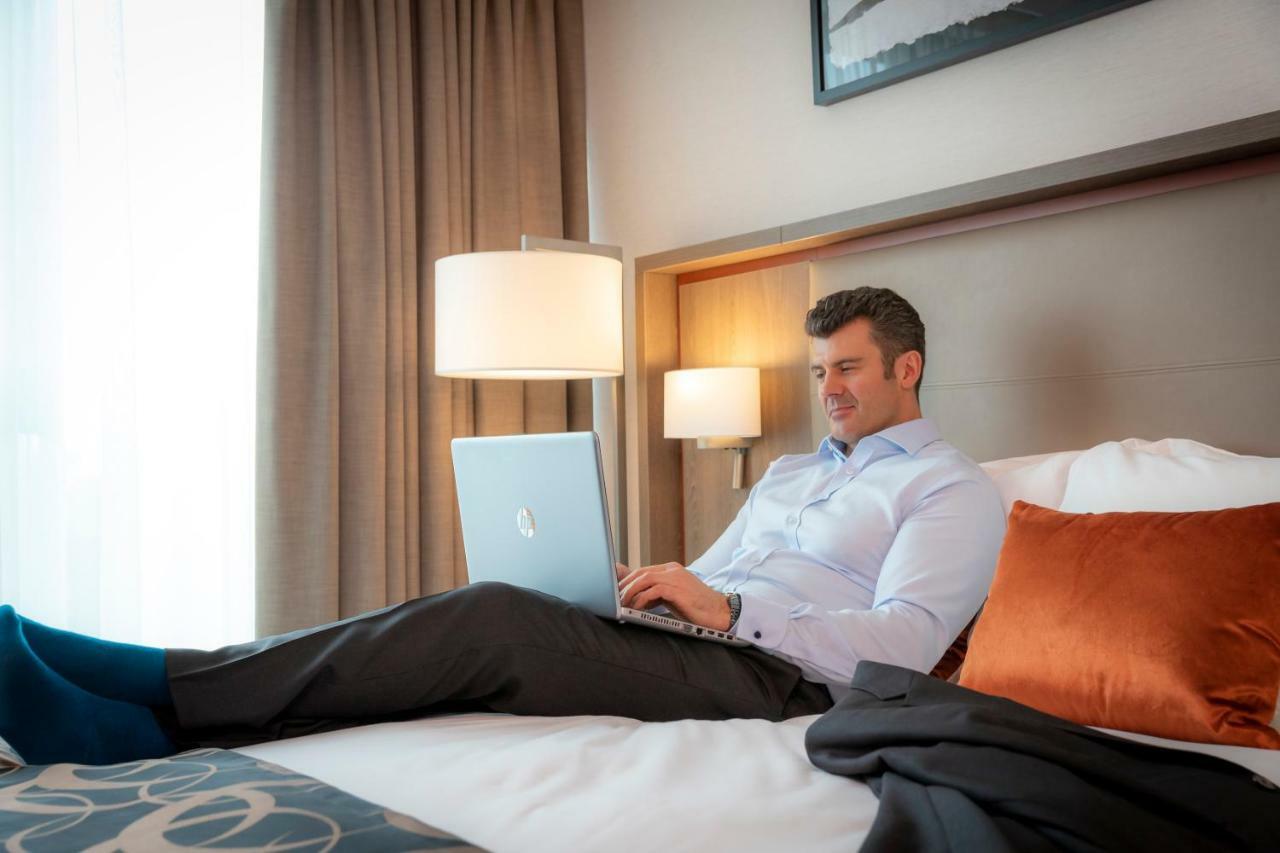 Clayton Hotel Dublin Airport Coolock Esterno foto A man working on a laptop in a hotel room
